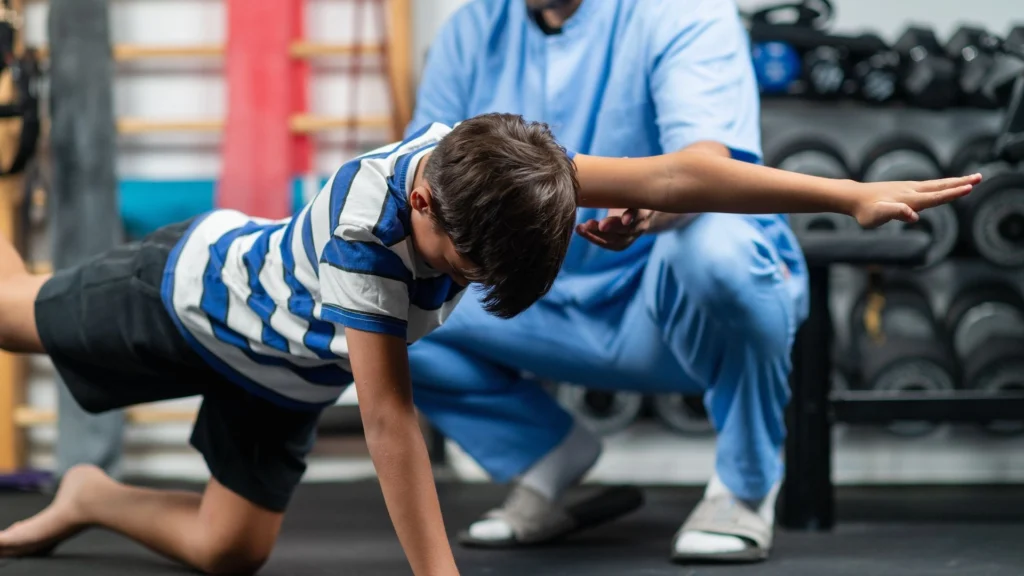 Physiotherapeut unterstützt Kind bei Bewegungstherapie in einer Praxis in Paderborn